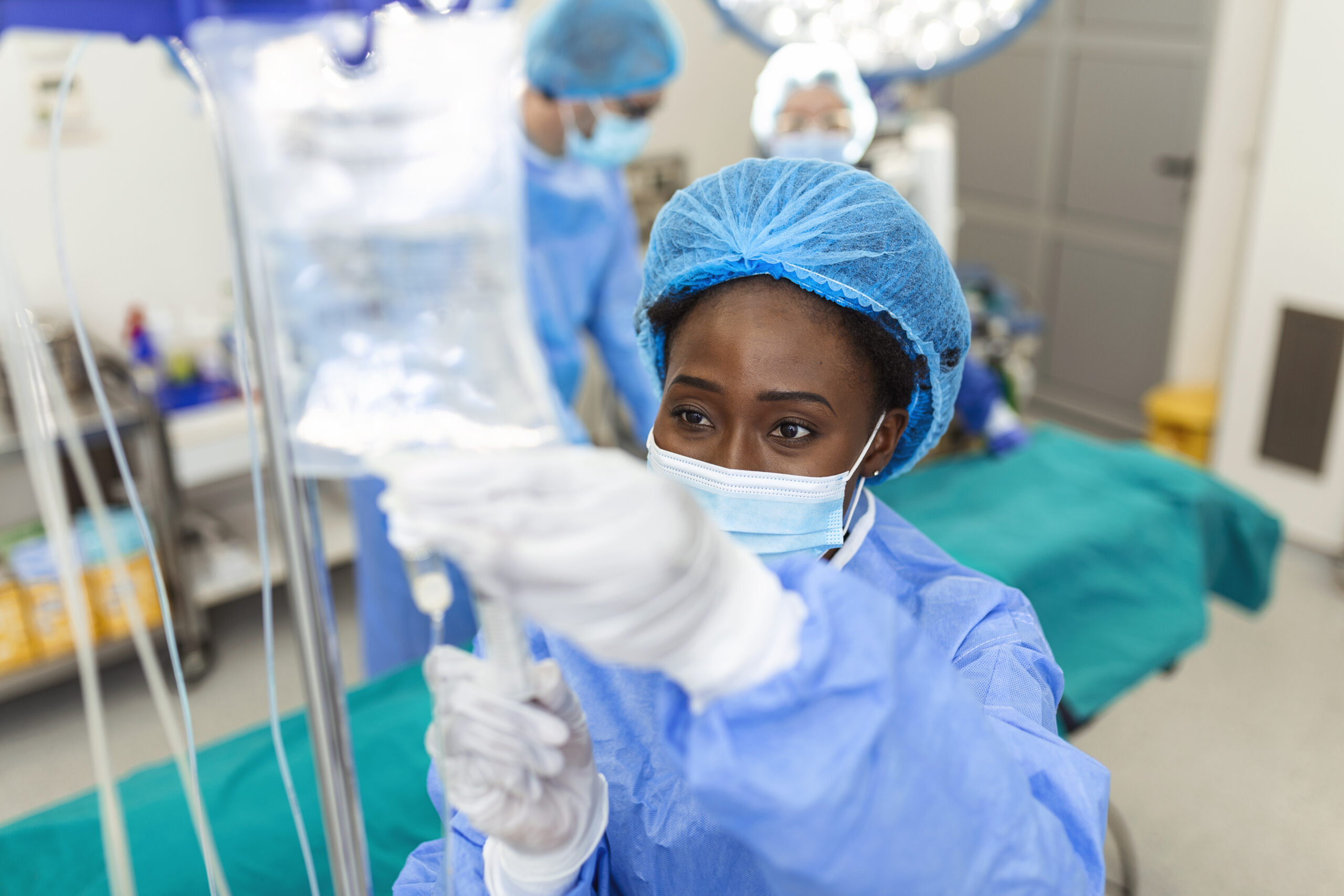 African american female Doctor in the operating room putting drugs through an IV - surgery concepts African american female Doctor in the operating room putting drugs through an IV - surgery concepts